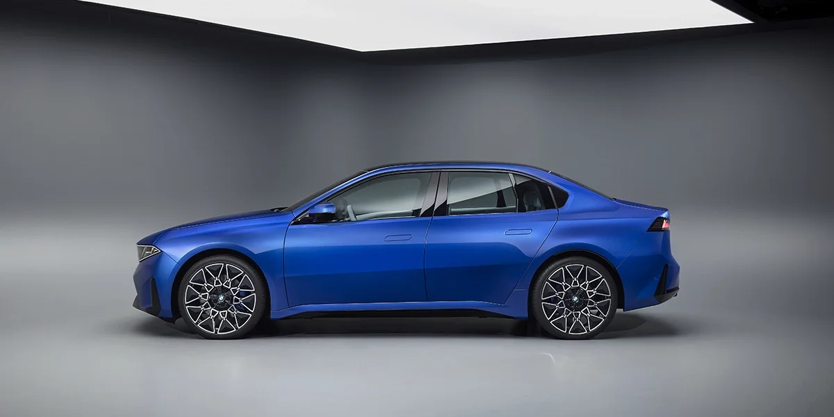 Studio side profile of 2027 BMW i3 electric sedan showing clean lines and wheel design.