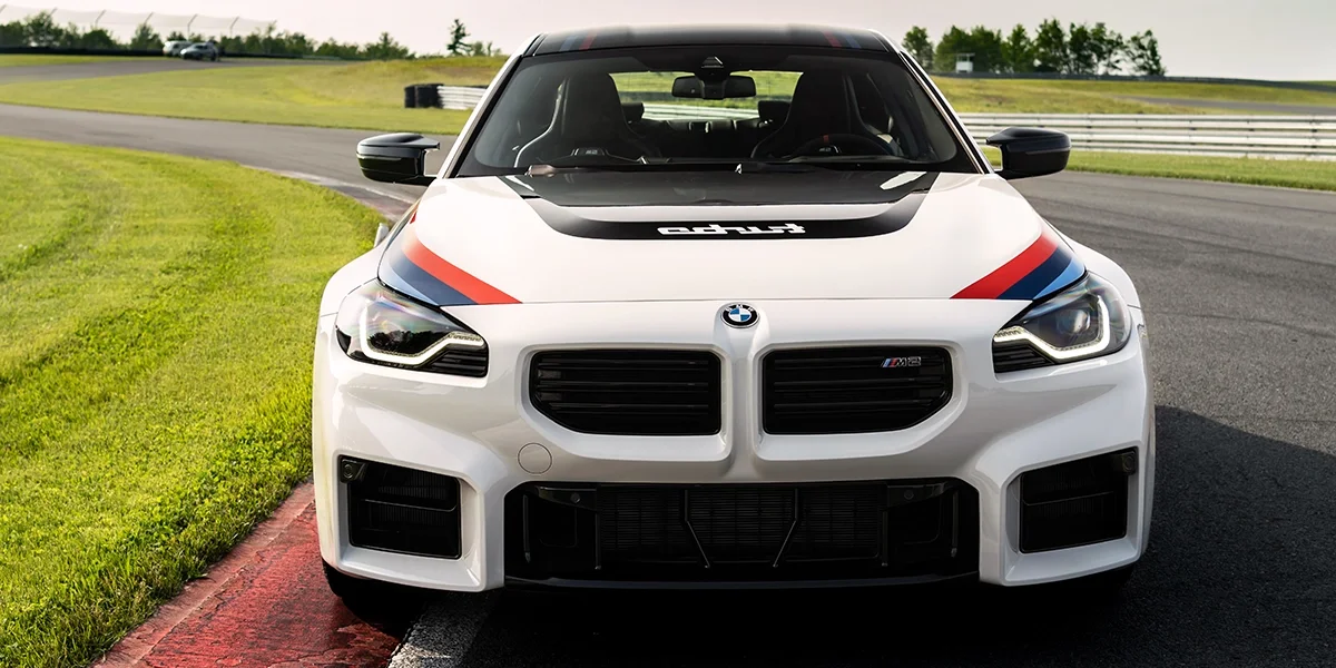 2026 BMW M2 Turbo front view on racetrack with carbon hood and M Performance livery.