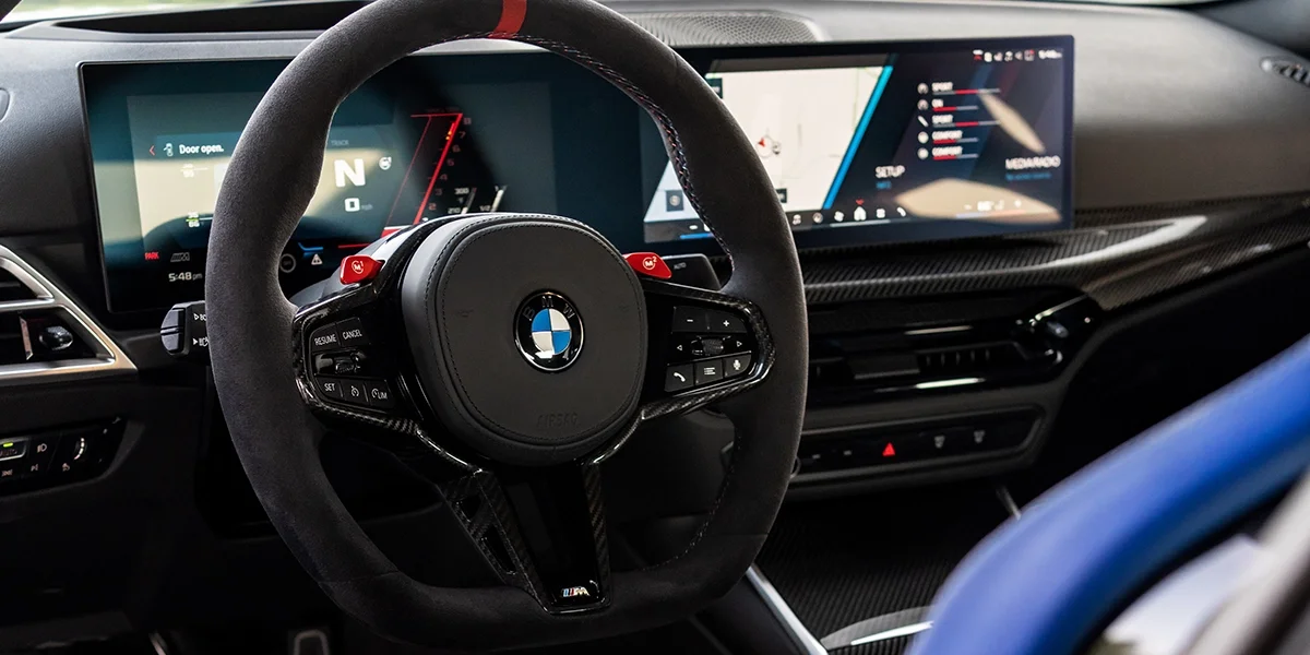 BMW M2 Turbo interior featuring Alcantara steering wheel, digital driver display, and carbon fiber trim.