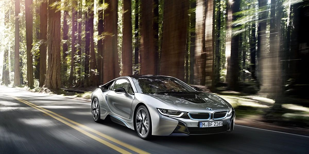 BMW i8 driving through forest road, emphasizing eco-friendly hybrid supercar performance