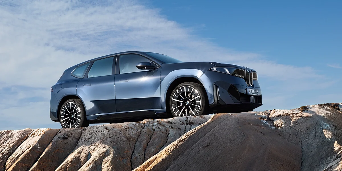 BMW iX3 50 xDrive front view with illuminated kidney grille against a clear sky.
