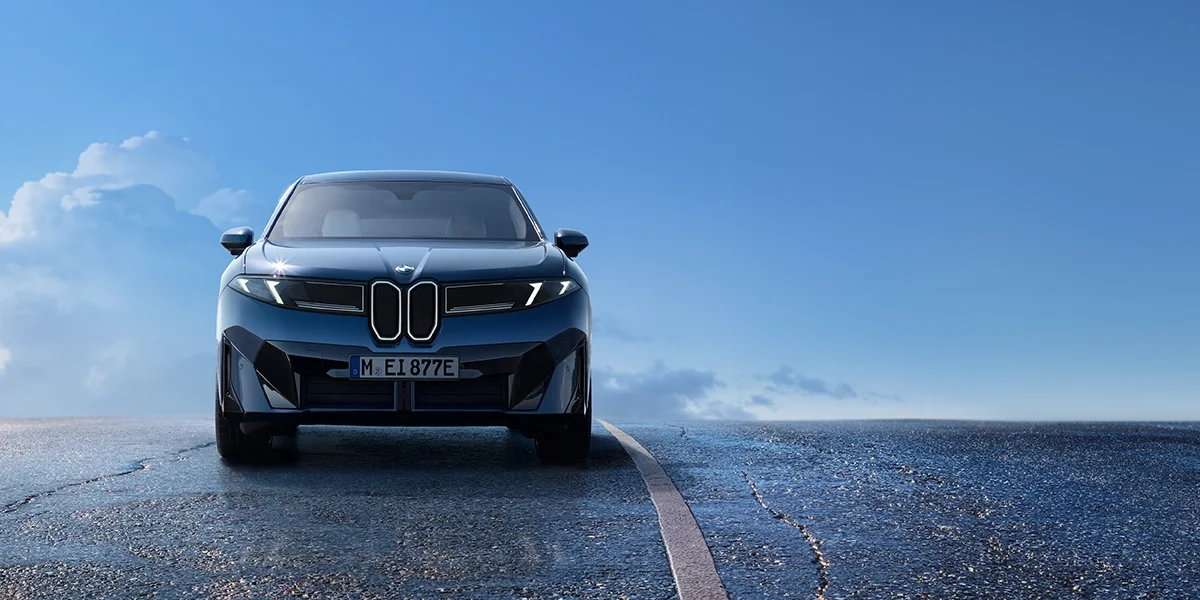 BMW iX3 50 xDrive front three-quarter angle in a mountain landscape.