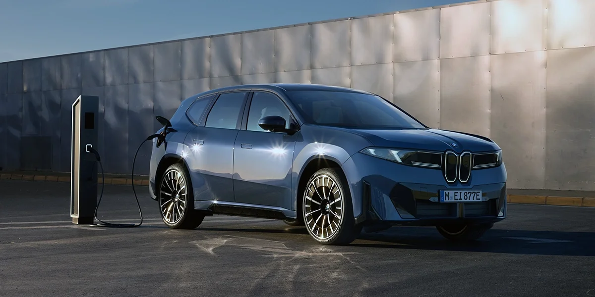 BMW iX3 50 xDrive driving on a highway curve in the mountains.
