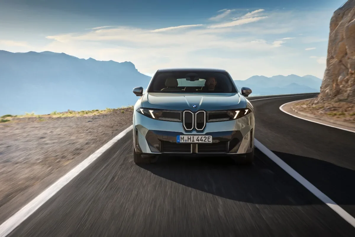 Gray BMW iX4 50 xDrive front view driving on a mountain road.