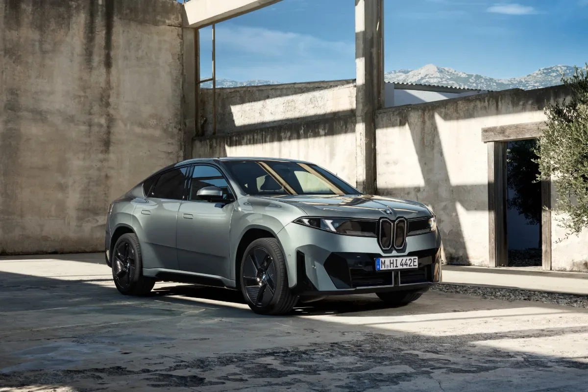 Gray BMW iX4 50 xDrive parked in front of a modern home.