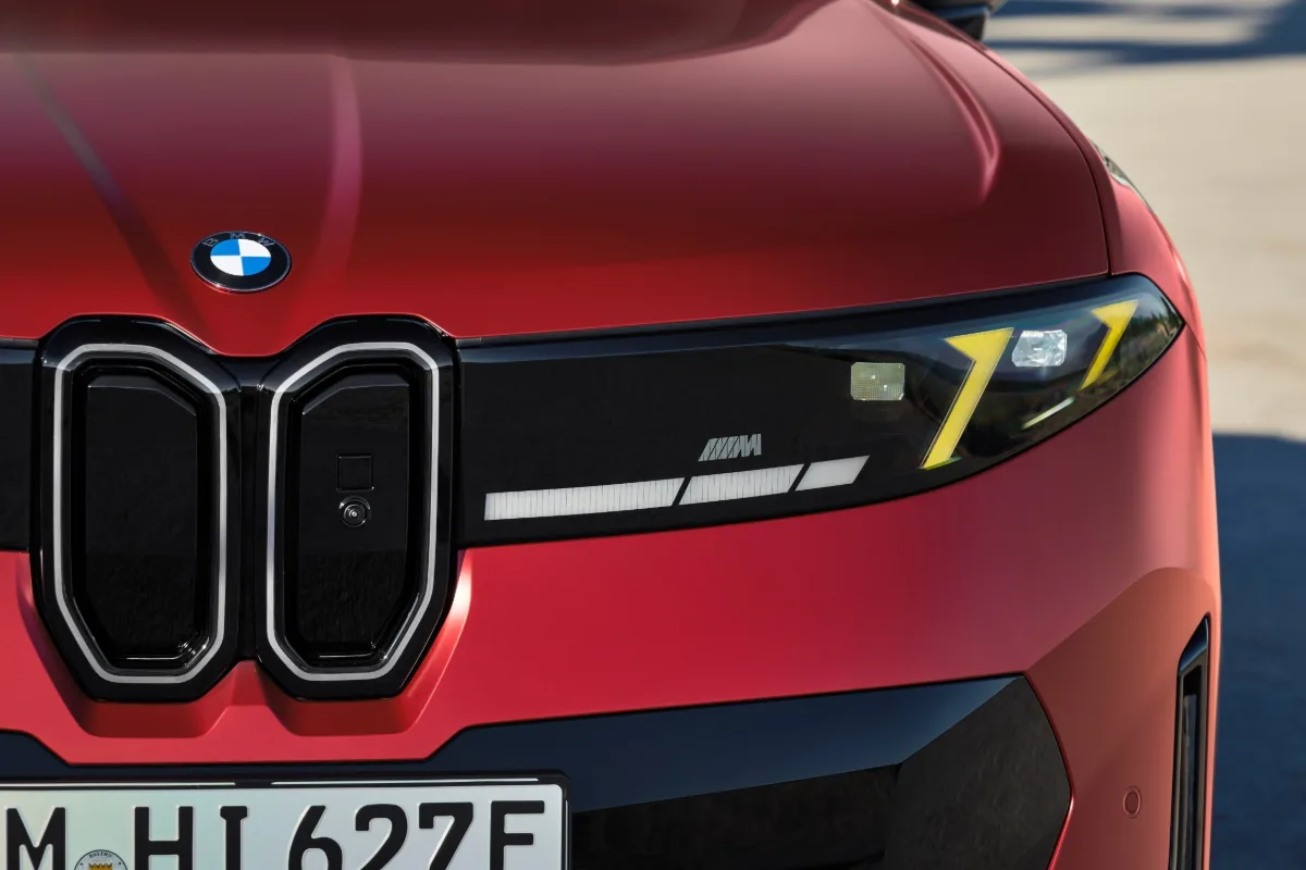 Close-up of the BMW kidney grille and slim headlights on a red iX4 M60 xDrive.