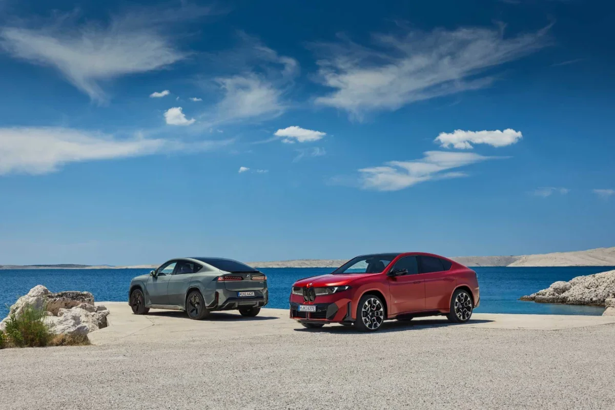 2027 BMW iX4 for sale in Palm Springs, CA, a red and a gray iX4 Sports Activity Coupe parked at a seaside overlook.